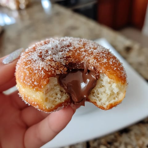 A person is holding a chocolate covered doughnut.