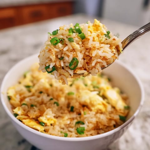 A spoon is scooping rice from a bowl.